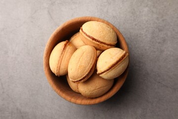 Delicious nut shaped cookies with boiled condensed milk in wooden bowl on gray textured table, top view