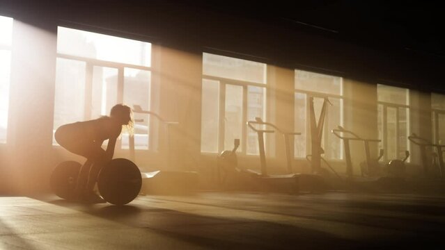 Close-up view of a woman performing barbell lunges. Silhouette of female athlete getting her hamstrings, quads and glutes strong and muscular. High quality 4k footage