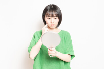 手鏡で顔を見ている若い女性