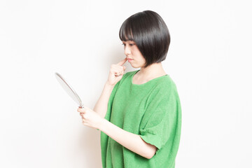 手鏡で顔を見ている若い女性