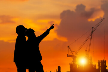 Fototapeta na wymiar Silhouette of Engineer and worker checking project at building site background, construction site at sunset in evening time