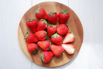 Fresh strawberries on wooden plate. ripe red strawberries on white wooden background. Fresh seasonal fruits.