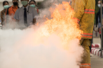 Showing how to use a fire extinguisher on a training fire for employees industry.Fire fighter concept.