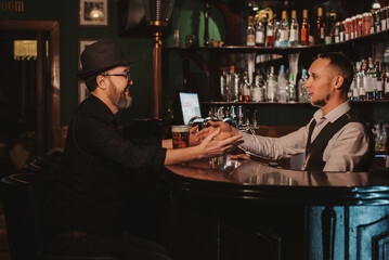 man communicates with a bartender at bar with beer in a pub