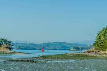 Red channel marker beacon between two islets at low tide.