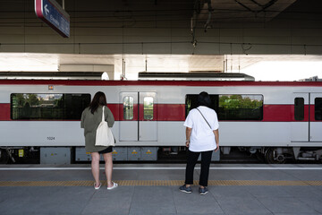 Asian young woman waiting the train in the platform of subway station and move of the train. Public transport concept.