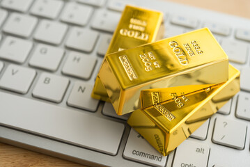 Gold bars on white keyboard computer background. Gold commodity trading market online investment concept. Digital technology for safe haven asset trading.