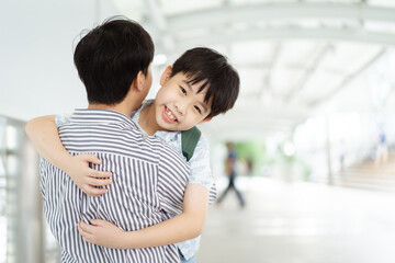 Fototapeta premium Happy cheerful Asian little boy running to his father at the railway or sky train station after his father returned from the traveling trip. Happy Asian family father and son concept.