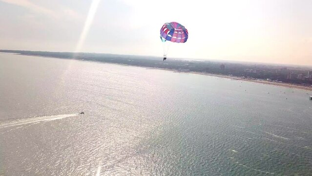aerial drone shot of boat pulling parachute over the sea in lignano parasailing