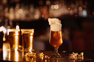 glass of unfiltered draft golden foam beer with on bar counter with ice in the restaurant