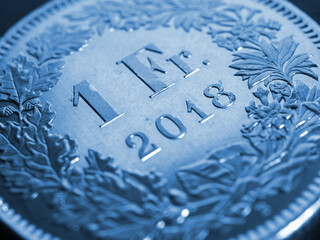 1 Swiss Franc coin close-up. Blue background or wallpaper about economy, business or banking. Money...
