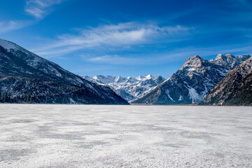 Fototapeta na wymiar Frozen lake in the middle of cold winter in northern China.Blue sky winter.Mountain in the background and frozen lake foreground.Winter landscape at Yilhun tso in Tibet.