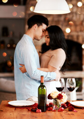 Love, wine and romance, couple hug on valentines day date at home with rose petals and bokeh. Date...