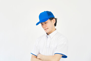 悩むポロシャツとキャップのユニフォームの男性　（引越し業者・運送業・作業員・宅配業者）