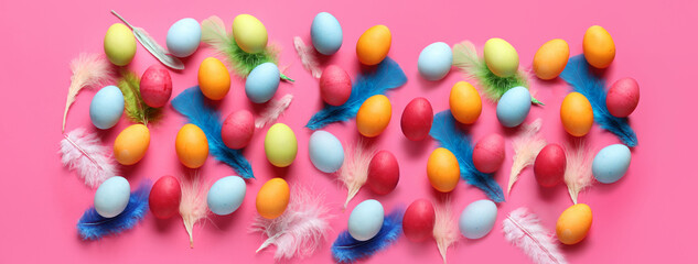 Colorful Easter eggs and feathers on pink background