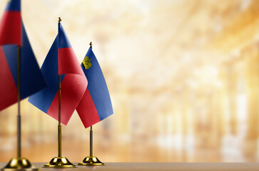 Small flags of the Liechtenstein on an abstract blurry background