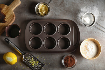 Composition with tray and ingredients for preparing tasty muffins on dark background