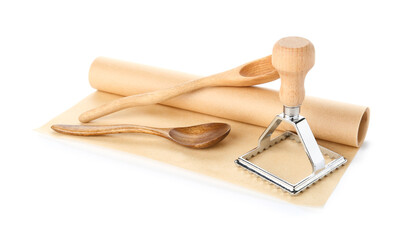 Roll of baking paper, spoons and ravioli cutter on white background
