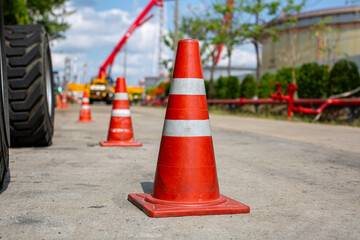Orange traffic cone in parking lot near hydraulic crane