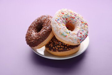 Plate with tasty donuts on lilac background