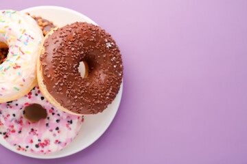 Plate with tasty donuts on lilac background