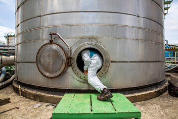 Male worker into  manhole fuel tank oil chemical protective clothing