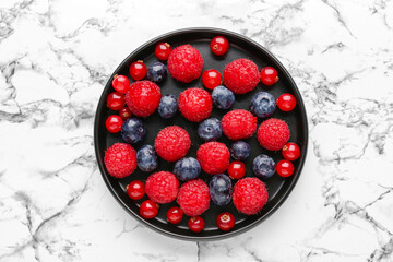 Plate of fresh berries on light background