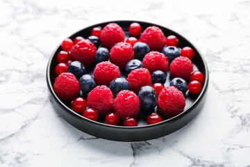 Plate of fresh berries on light background