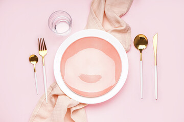 Table setting with golden cutlery on pink background