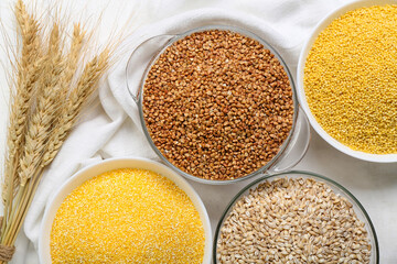 Bowls with different cereals and spikelets on light background, closeup