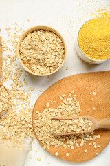 Bowls of oatmeal flakes and corn grits on light background