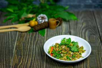 Spicy minced catfish salad with herbs northeastern thai food mellow taste served on a dark wooden table.