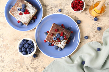 Plates with pieces of cottage cheese casserole and berries on light background
