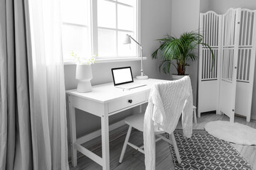 Workplace with laptop near window in light room