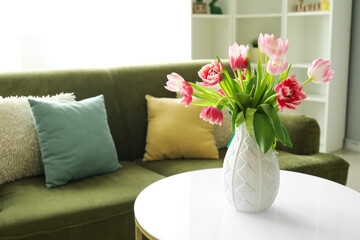 Vase with pink tulips on table in modern living room, closeup