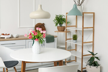 Vase with beautiful tulips on dining table in kitchen