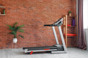 Interior of room with modern treadmill near brick wall