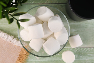 Bowl with delicious marshmallows on green wooden table