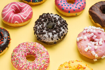 Different delicious donuts on yellow background
