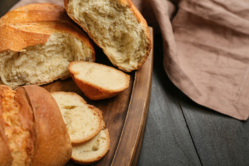 Cutting board with fresh sliced bread on black wooden background