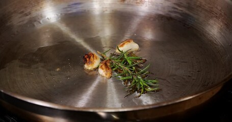 Rosemary and garlic searing in a stainless steal pan 