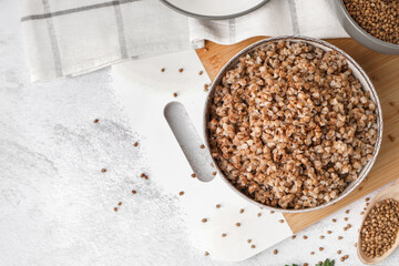 Board with bowl of tasty buckwheat porridge on white table