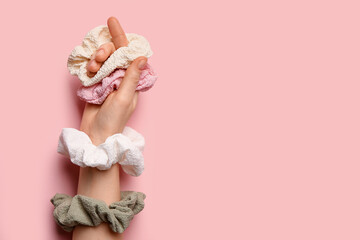 Female hand with different scrunchies on pink background