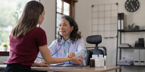 Fototapeta premium Middle aged female pediatrician listening to young woman's complaints with health problems And write down on the medical history paper during the treatment. health concept
