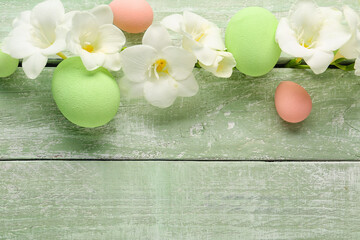 Composition with beautiful freesia flowers and Easter eggs on color wooden background