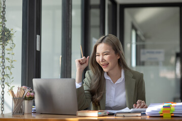 Happy excited young successful business woman and working online at the table in office, Asian business woman.