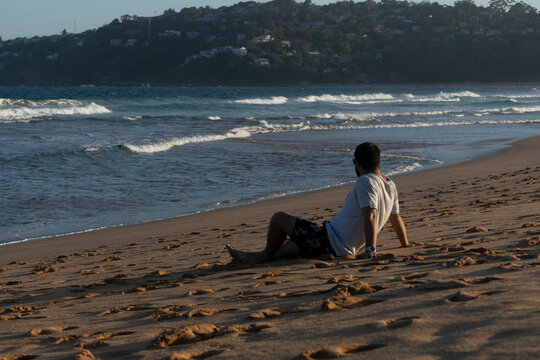 Man Sitting Relaxed On The Beach Looking Out To Sea