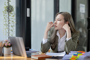 Asian businesswoman are stressed and tired from work sitting at desk in the office, feeling sick at work, stress from work. 