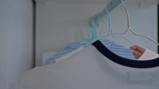 shop assistant moving hangers with female clothes on the rack slow motion