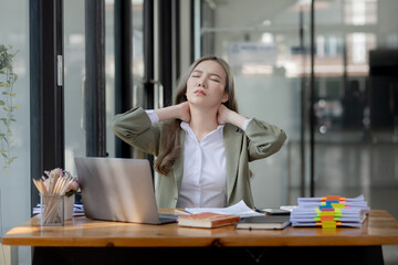 Asian businesswoman are stressed and tired from work sitting at desk in the office, feeling sick at work, stress from work.  - Powered by Adobe